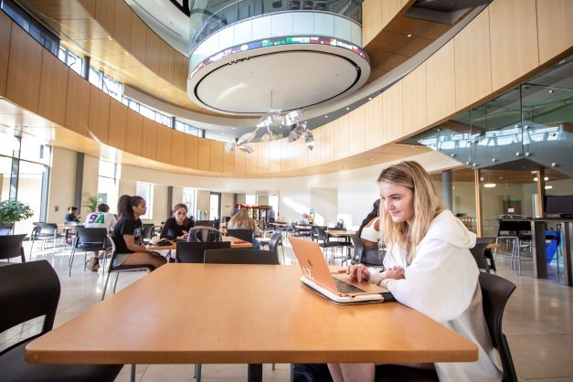 female student works on laptop in BEC Rotunda