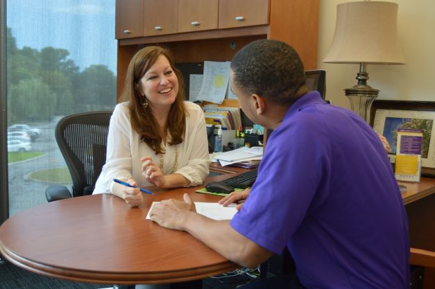 Female counselor meeting with student at desk. 