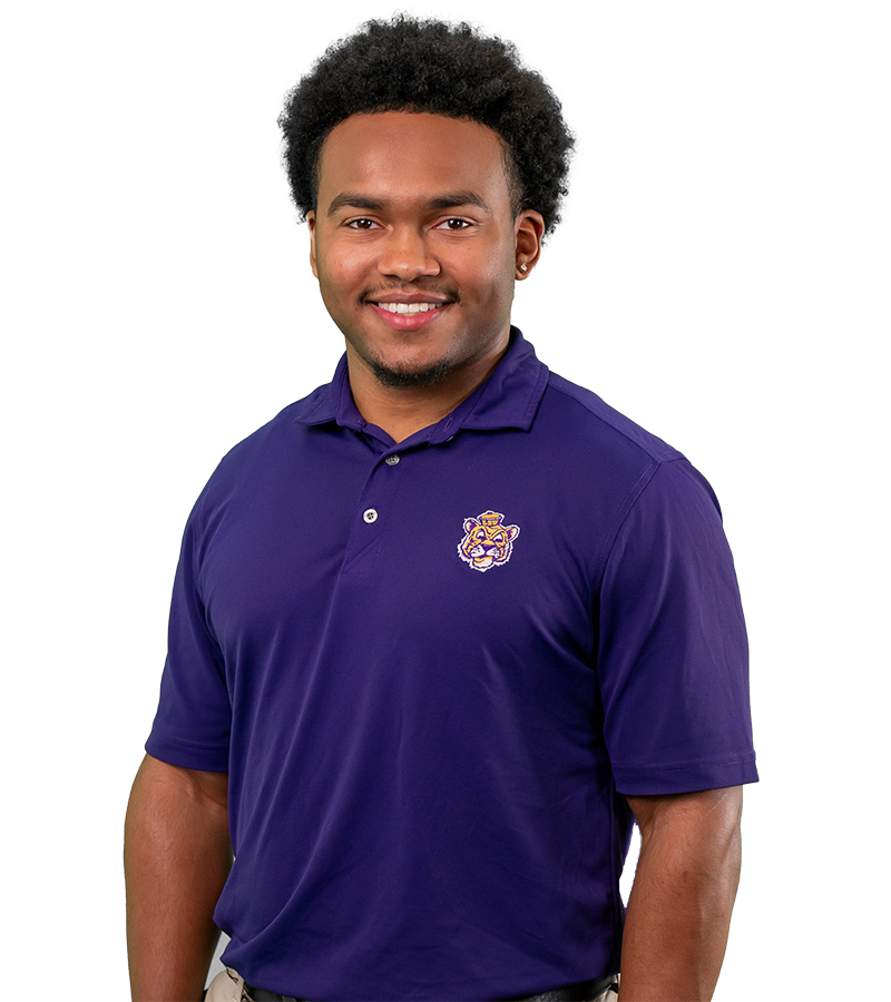 Mekhi Glover wears a purple polo with a retro Mike the Tiger logo. He smiles warmly.