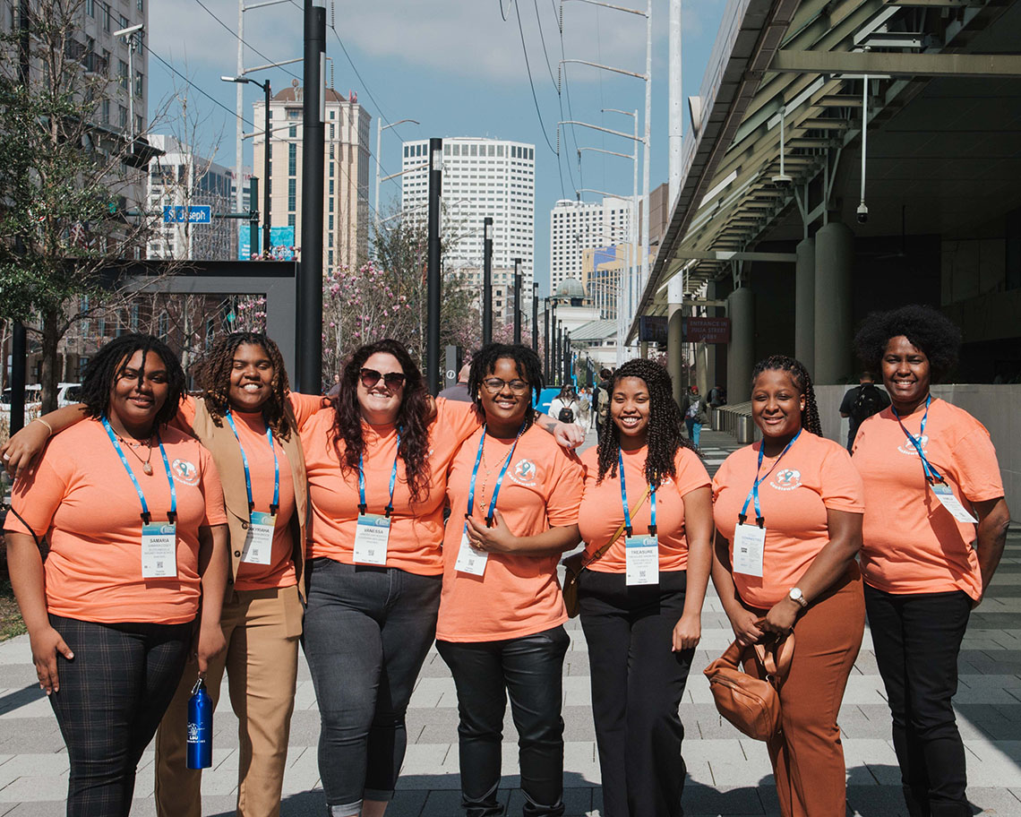 a group of people in orange shirts stand outside