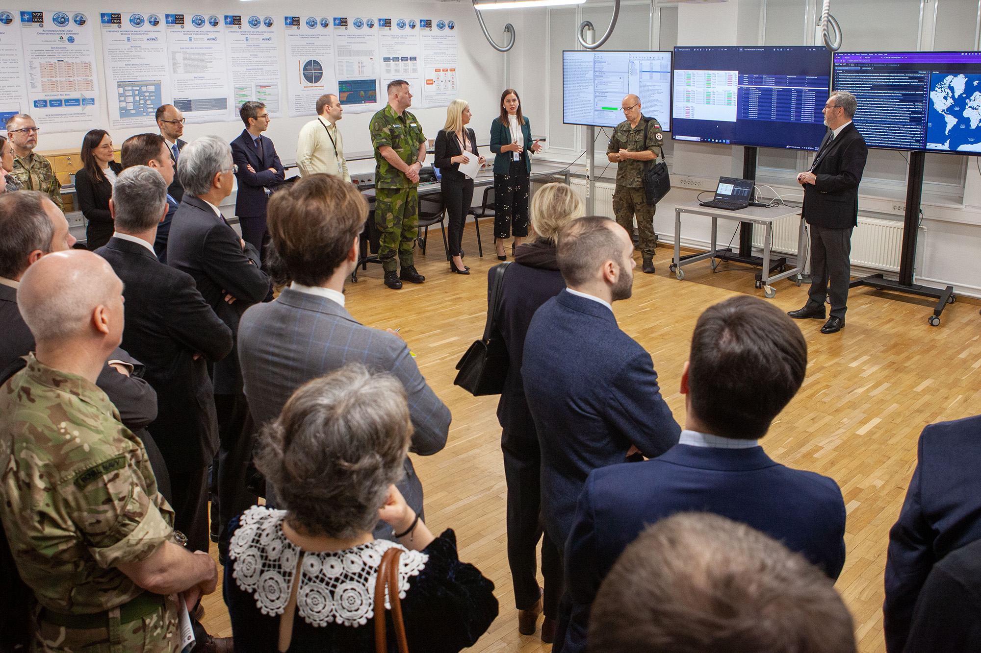 A group of people in a computer room listening to a speaker.