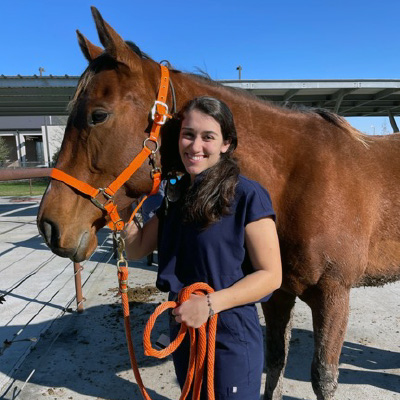 Mya stands with a horse. 